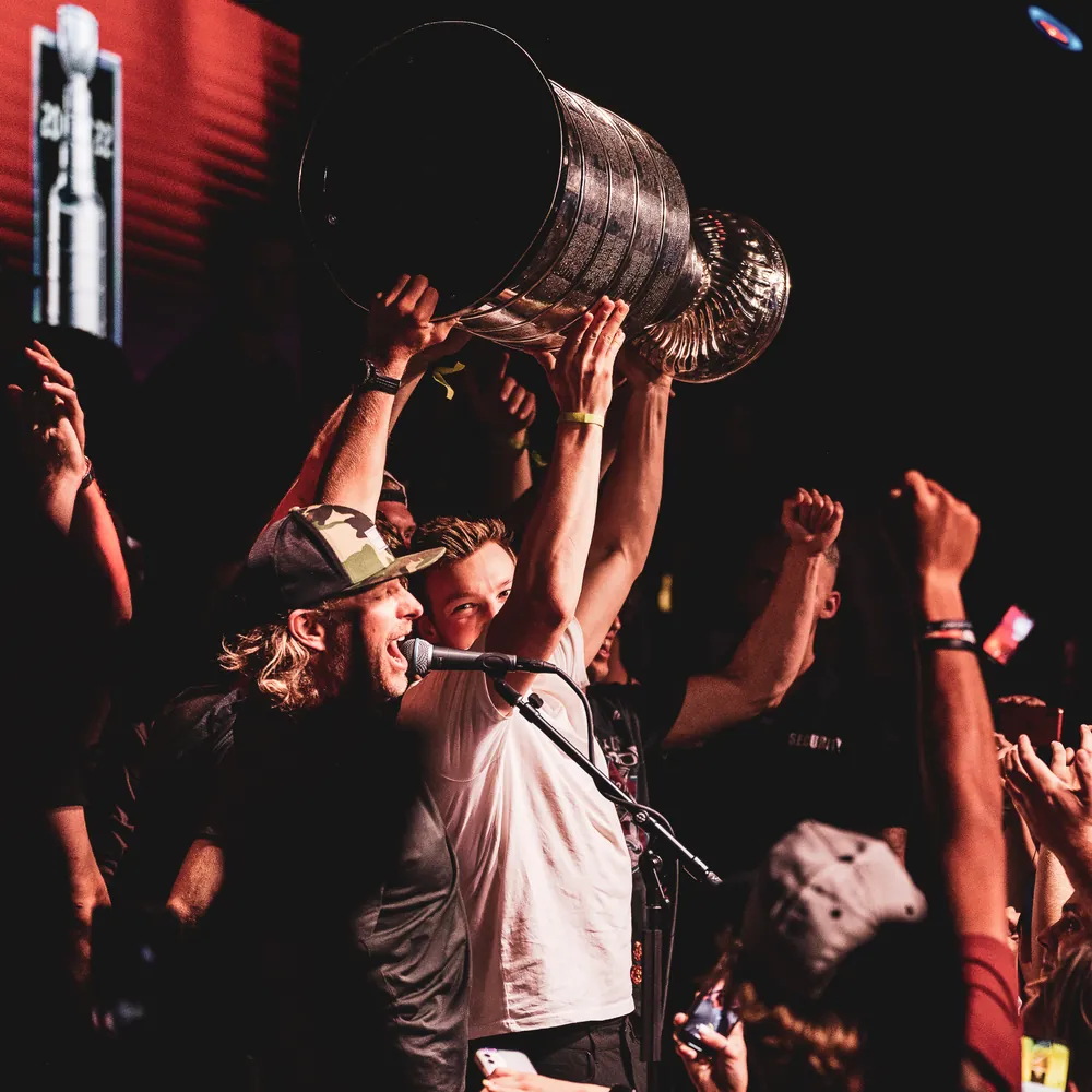 Performer singing on stage as the crowd cheers and lifts a giant drink bucket overhead at Dierks Bentley's Whiskey Row